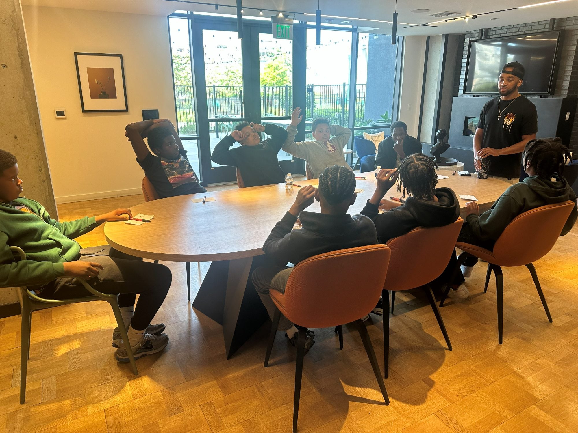 Young men around a table raising their hands during a Day2Day session
